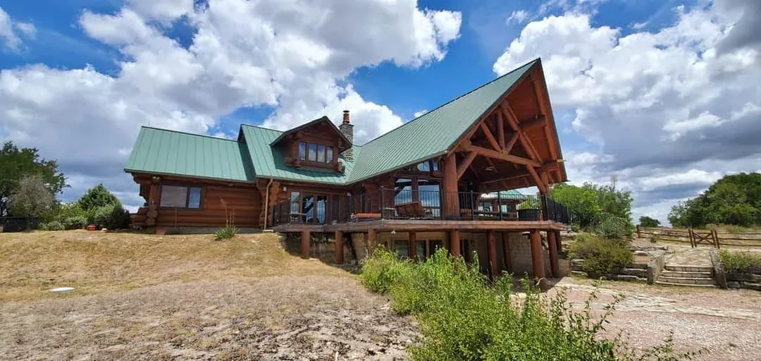 Restained log home with green metal roof in the Texas Hill Country near Kerrville